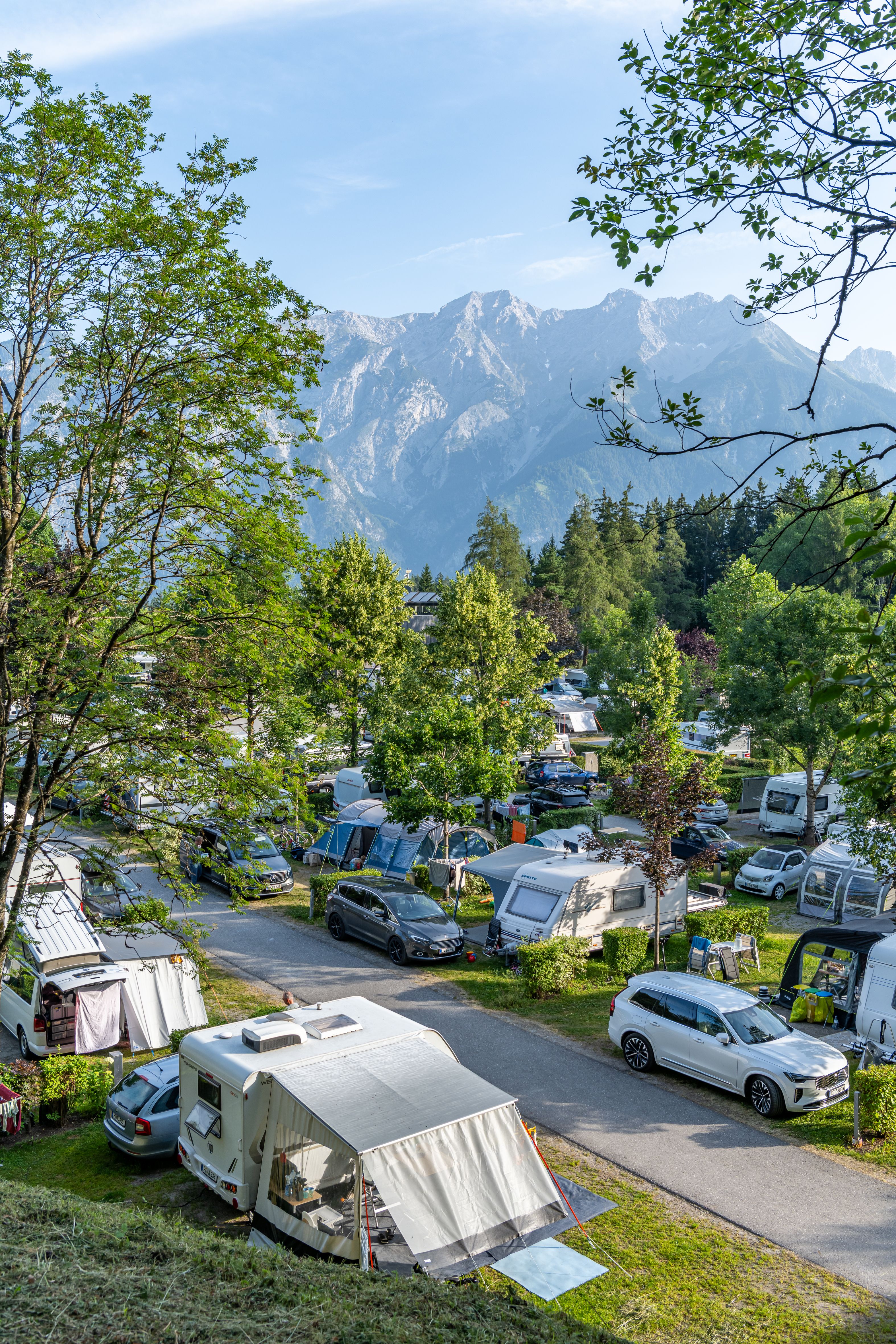Campingplatz mit Wohnwagen und Zelten vor Bergpanorama am Natterer See