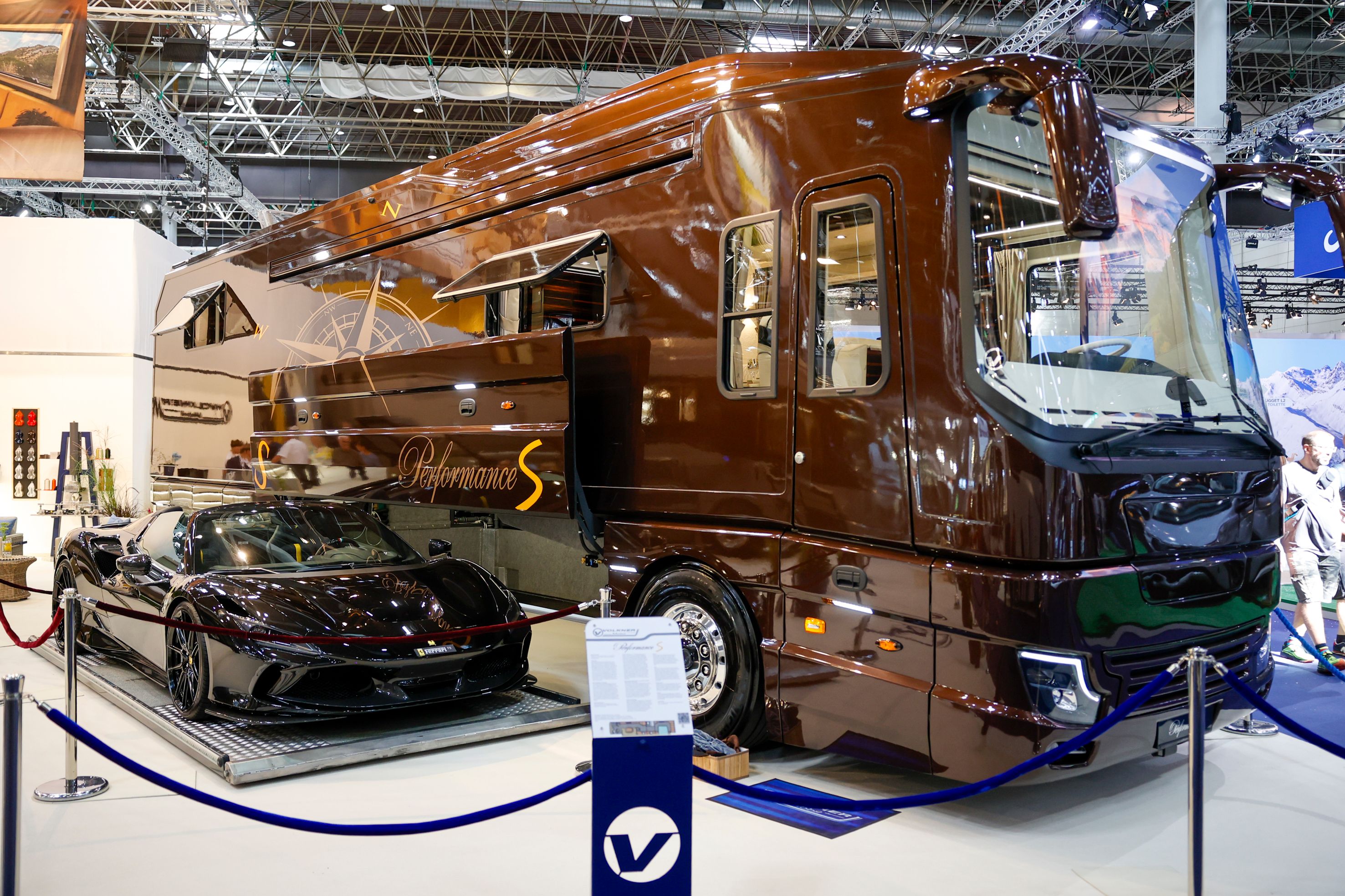 Luxuriöses Liner-Wohnmobil mit Sportwagen in der Heckgarage auf dem Caravan Salon